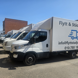 Fyra flyttbilar parkerade i linje på en stor gårdsplan.